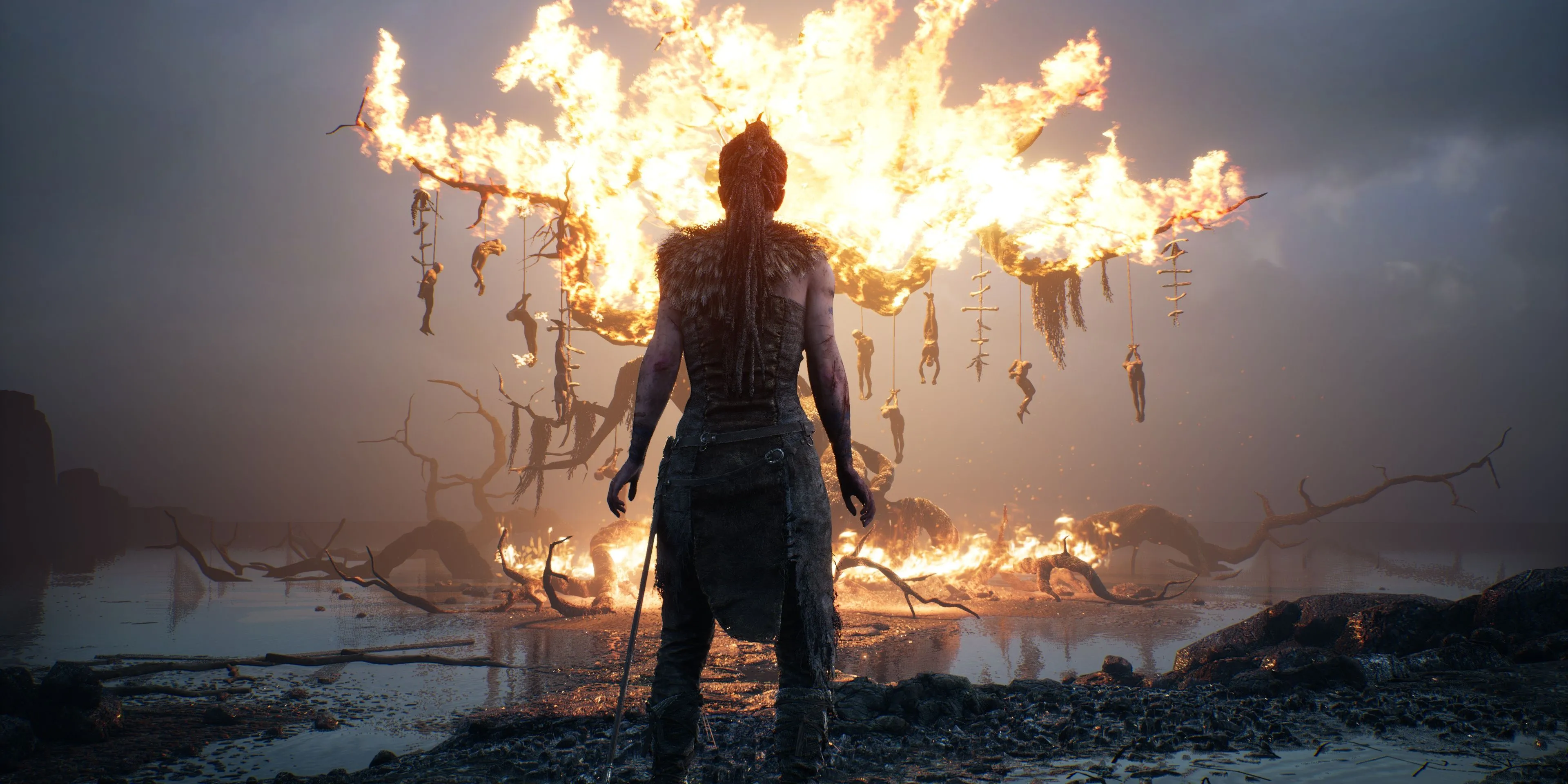Senua đứng trước một cái cây đang bốc cháy, hình ảnh đầy ám ảnh từ Hellblade: Senua's Sacrifice